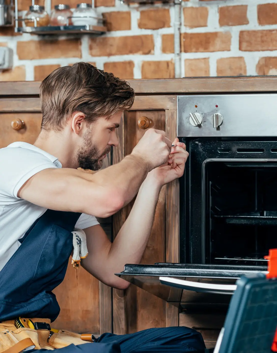 Man repairing an oven in kitchen.