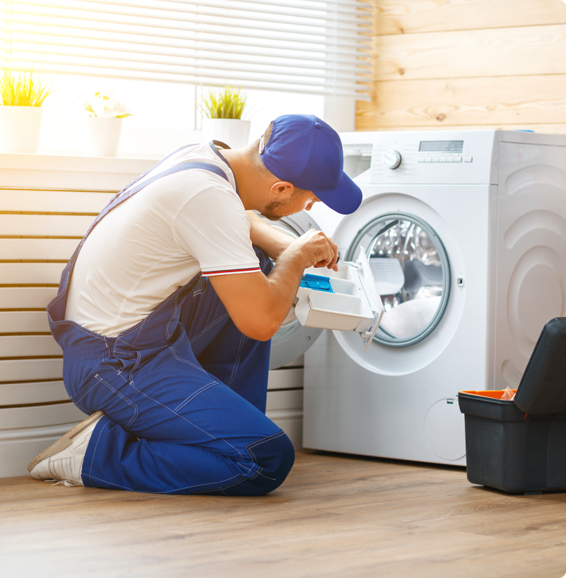Technician repairing washing machine in laundry room.